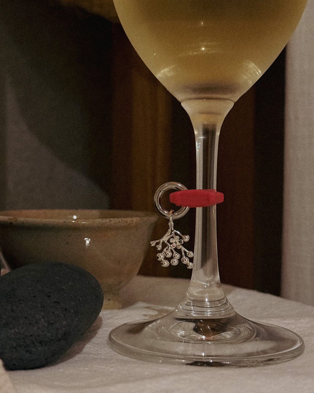 Kiki's charm clipped to a wine glass stem in a dark bar