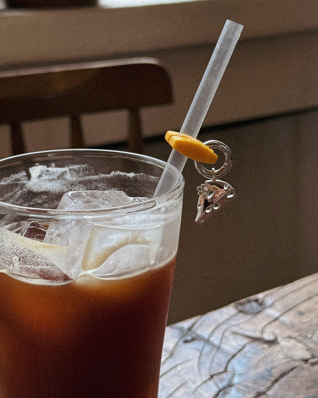 Kiki's charm clipped to the straw of an iced coffee